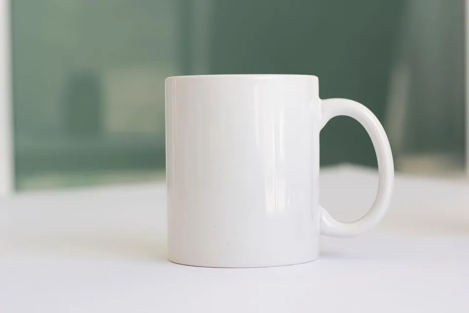 Foto ilustrasi mug keramik putih polos di atas meja